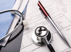 stethoscope and pen resting on a sheet of medical lab test results, with patient file and x-ray or mri film