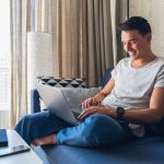 young-attractive-man-sitting-on-sofa-at-home-working-on-laptop-online-using-internet (1) (1)