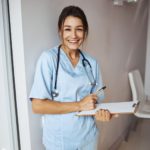 joyful-female-doctor-with-clipboard-standing-in-cl-2021-09-04-14-34-18-utc