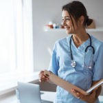 Cheerful female doctor holding folder with papers